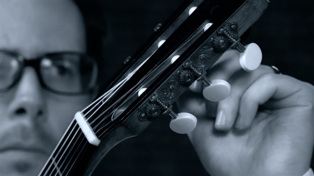 Close-up of Sam Desmet tuning his classical guitar, black and white