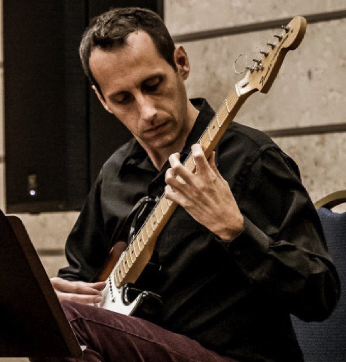 Sam desmet playing electric guitar in a performance setting, focused on music and artistry.