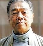 A senior man with gray hair and a calm expression, wearing a neutral jacket.