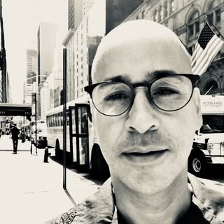Close-up of painter Frank Hodelin with cityscape background, black and white photography.
