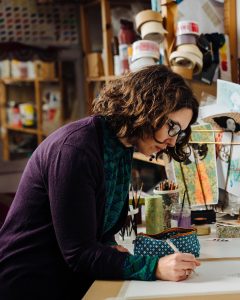 Sam desmet artist working on art projects in studio with creative supplies and colorful artworks.