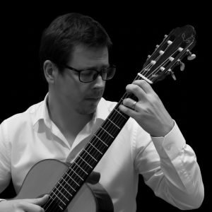 classical guitarist Sam Desmet playing guitar in black and white.